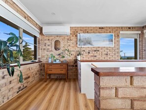 A bathroom with a wooden vanity, a mirror, and a large window. - Absolute Beachfront Escape · Ocean Views · Family Luxury (Halls Head)