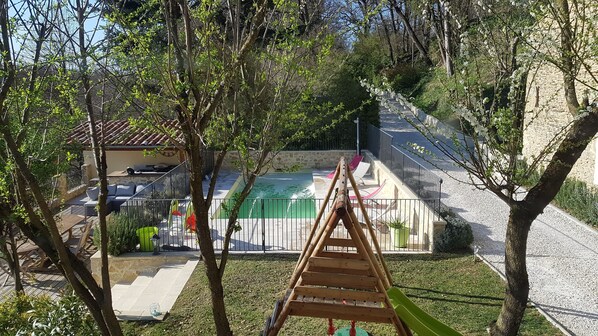 A pool area with a wooden swing set, stone walls, and outdoor seating. - Pool house 10 people Crest, Saou Valence (Divajeu)
