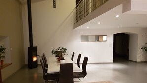 Un comedor moderno con techo alto, una mesa central y sillas.