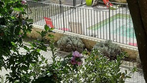 Zona exterior cercada con piscina, rodeada de vegetación y un edificio de piedra.