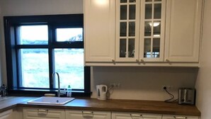 Una cocina con armarios blancos, encimera de madera, una ventana con vistas y un lavamanos.