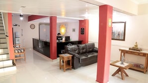 A modern living room with a leather sofa, a wooden coffee table, and a desk with a computer. - Hotel Colonial (Porto Ferreira)