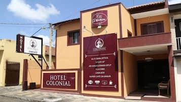 A hotel named Hotel Colonial with a signboard indicating amenities like Wi-Fi, TV, and a split air conditioning system.