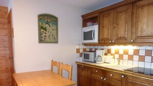 A kitchen with wooden cabinets, a tiled backsplash, a microwave, a coffee maker, and a toaster.