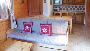 A cozy room with a sofa, a small table, and a kitchenette area.