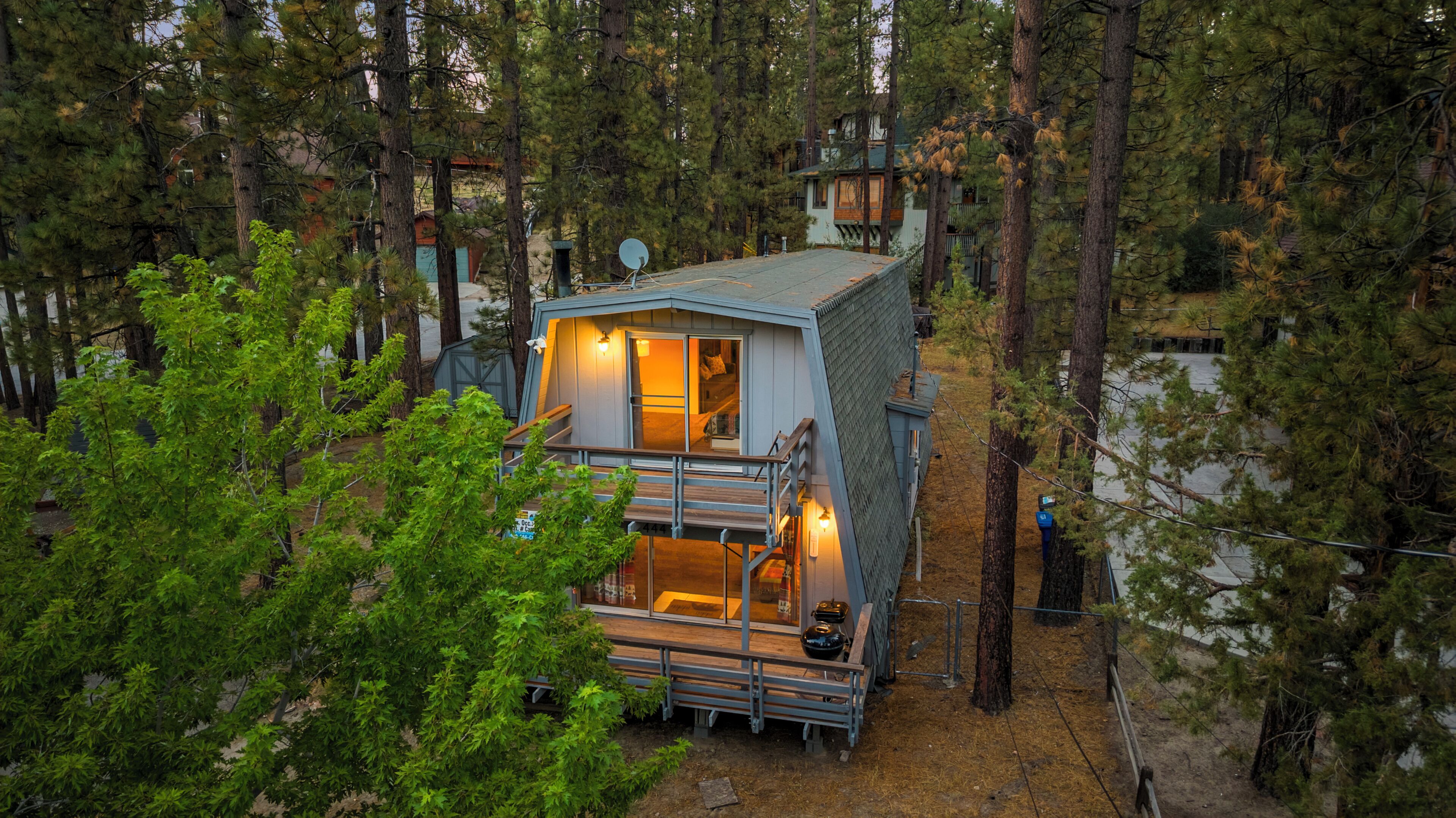 Une cabane dotée d’un balcon, entourée d’arbres.