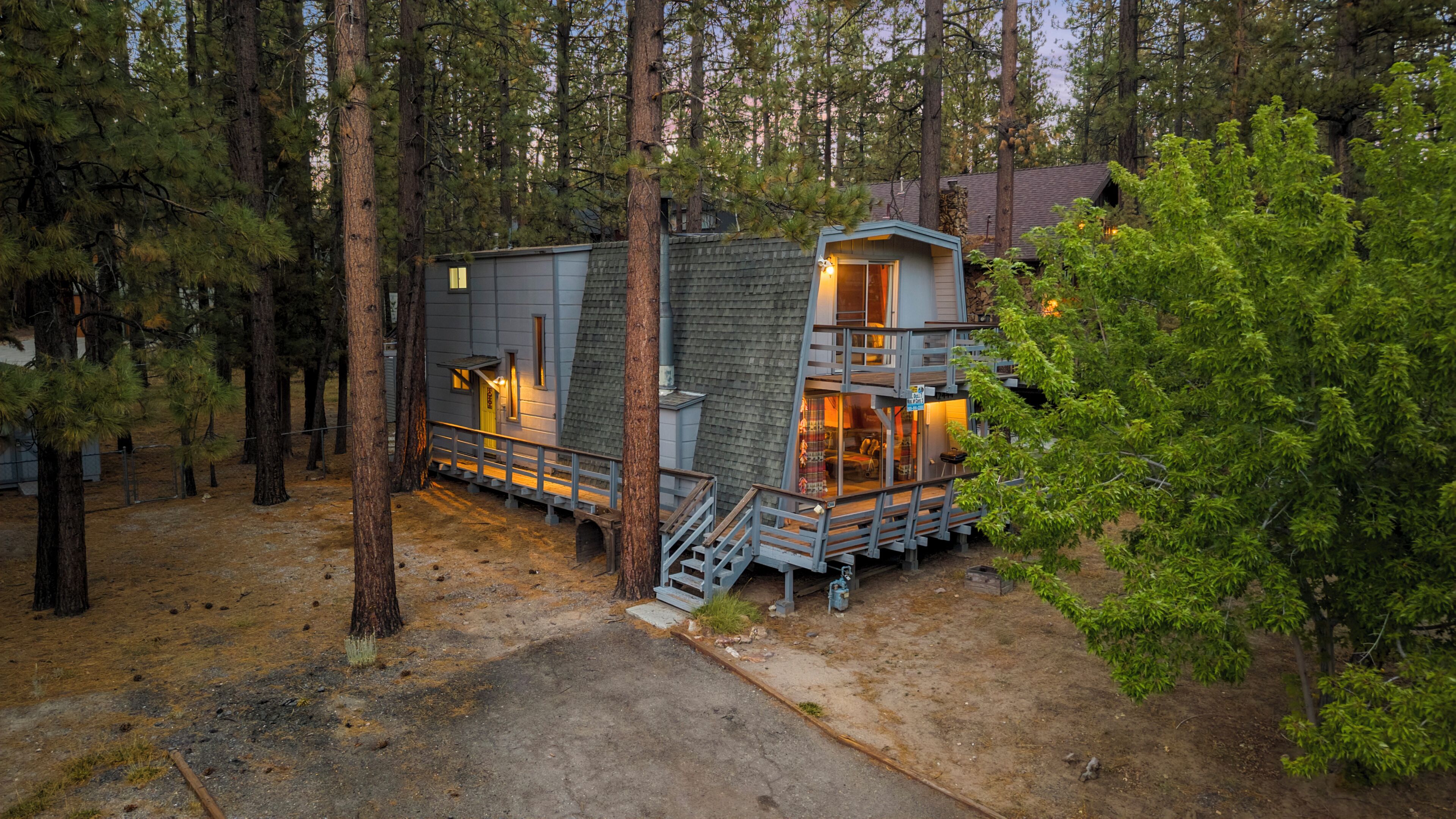 A cabin with a deck, a staircase, and a fire pit area.