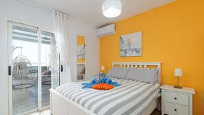 Un dormitorio con cama, mesita de noche, lámpara y un cuadro en la pared.