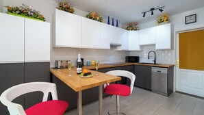 Una cocina moderna con armarios blancos, encimera de madera y un taburete rojo.