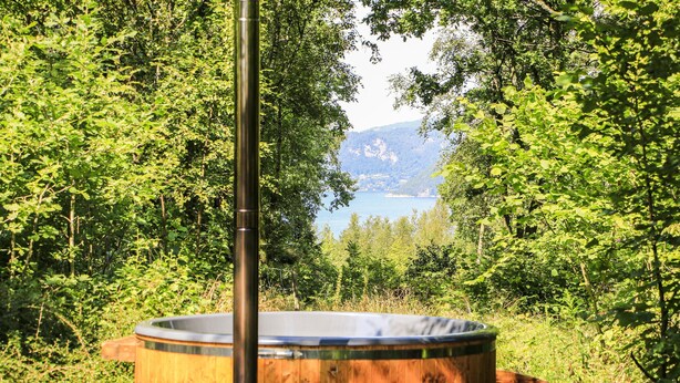 Ein Whirlpool in bewaldeter Landschaft mit Blick auf einen See und Berge.