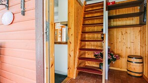 Eine Holztreppe führt zu einem Raum mit Holzboden, einer Holzwand und einem Fass.