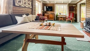Ein gemütliches Wohnzimmer mit Holztisch, Sofa, Sesseln und Kamin.
