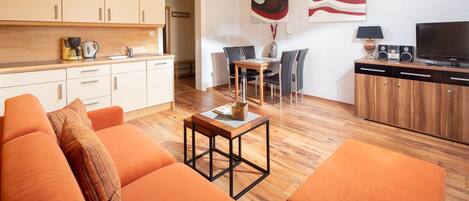 A modern living room with a sofa, a coffee table, and a dining area with chairs.