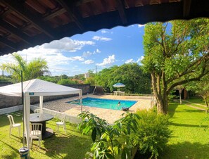 A covered outdoor swimming pool with a table and chairs, surrounded by greenery and trees. - Seasonal and monthly rentals(consult) (Itu)