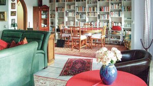 Una sala de estar con un sofá verde, una mesa roja y una estantería llena de libros.