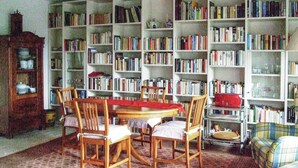 Una biblioteca con una mesa redonda de madera y sillas, rodeada de altas estanterías llenas de libros.