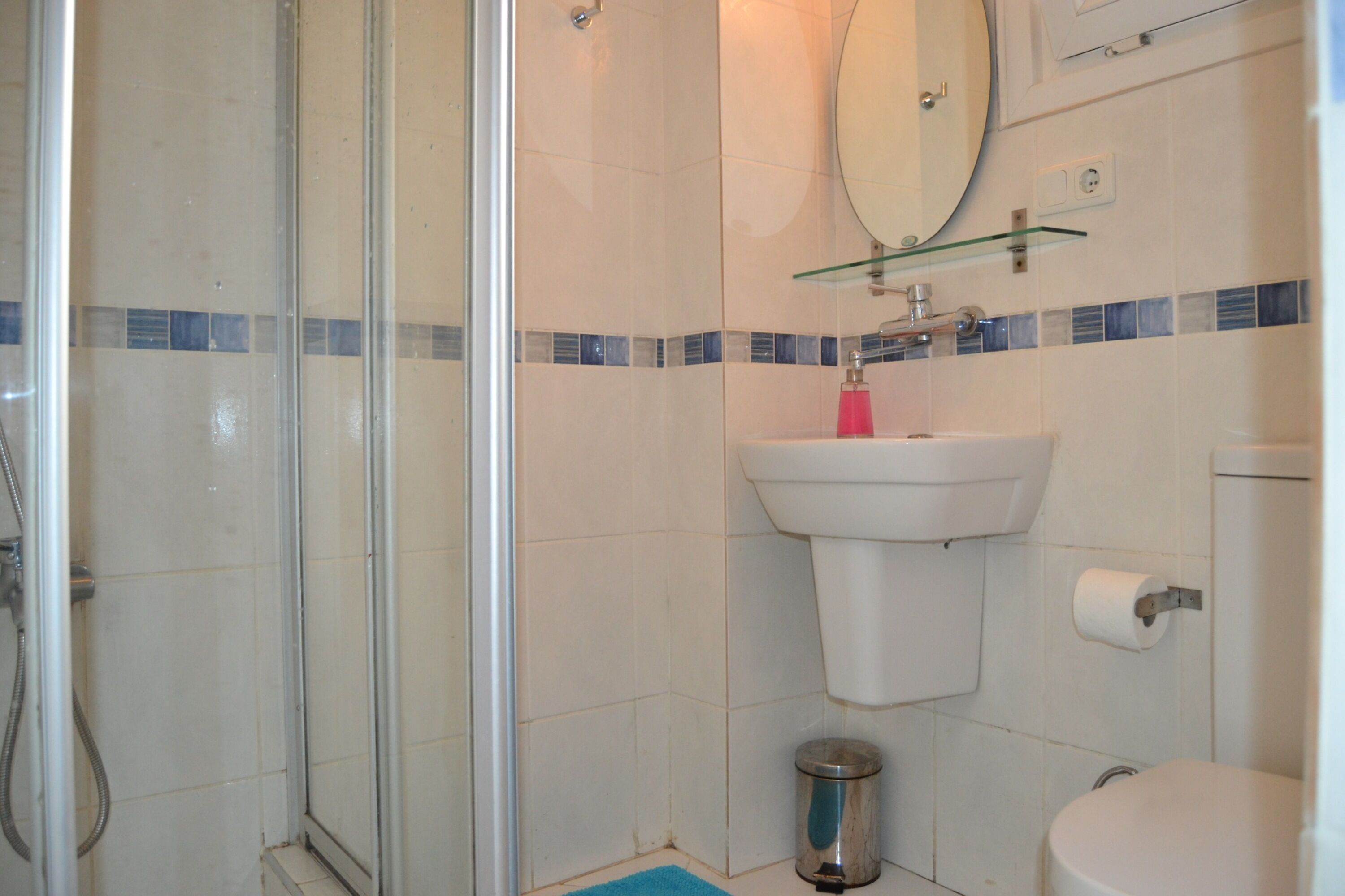 Une salle de bain avec une douche à parois de verre, un lavabo blanc et des toilettes.