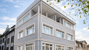 A multi-story building with a grey facade, white window frames, and a balcony on the upper floor. - Emirhan Guest House & Suites (Istanbul)