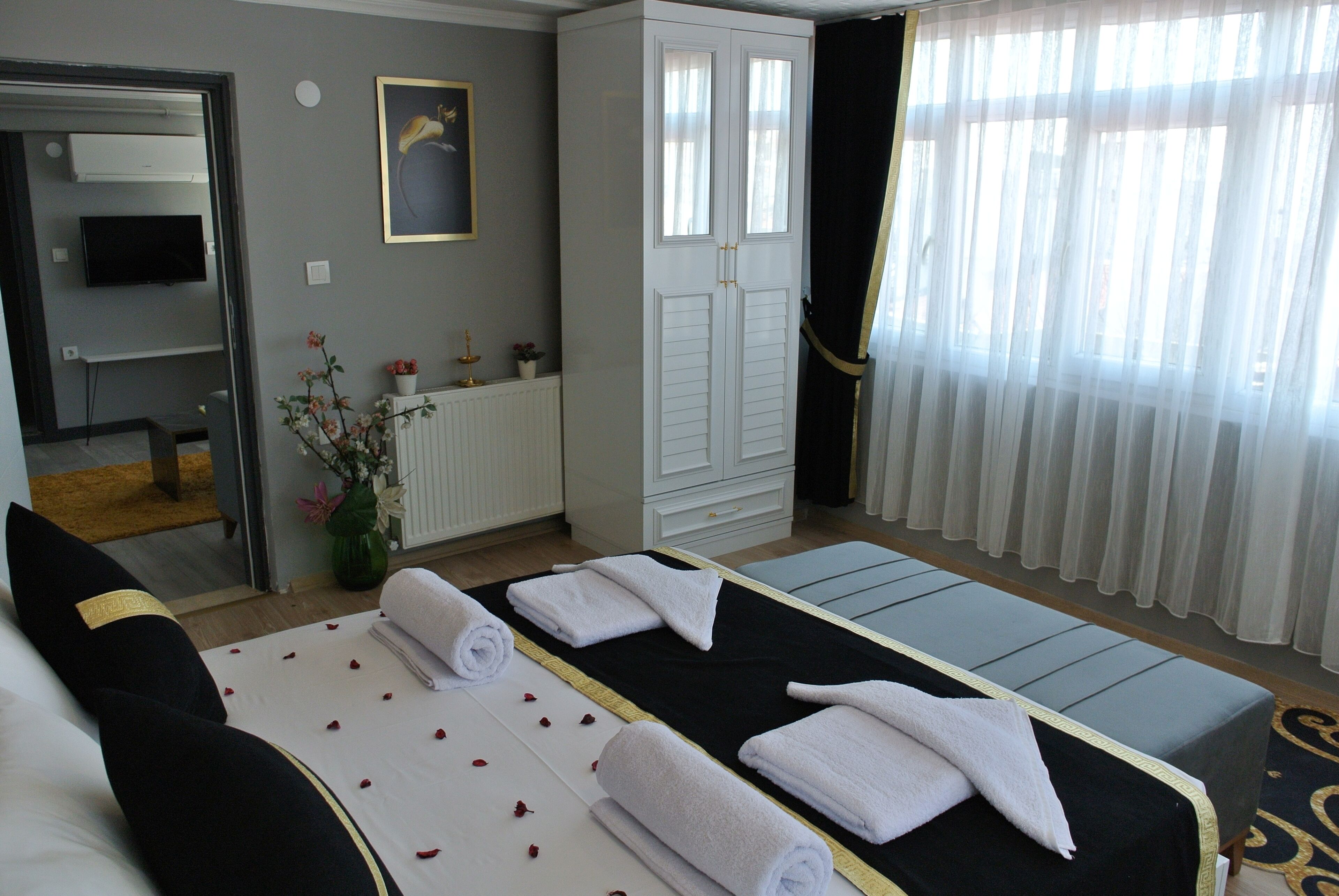 A hotel room with a bed, a sitting area, a wardrobe, and a television.
