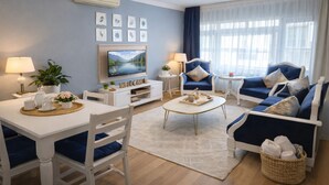 A modern living room with a sofa set, a dining table with chairs, a coffee table, a TV, and a 'WELCOME' sign on the wall. - Emirhan Guest House & Suites (Istanbul)