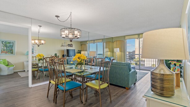 A modern living room with a dining area, large windows, and a view of the city. - Ocean view condo, fully renovated + Free Attraction Tickets! (Myrtle Beach)