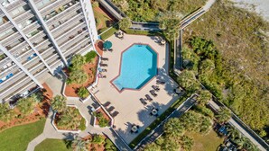 An aerial view of a hotel with a swimming pool surrounded by sun loungers and a garden area. - Ocean view condo, fully renovated + Free Attraction Tickets! (Myrtle Beach)