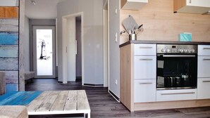Une cuisine moderne dotée d’un four encastré et d’un coin repas avec une table et un banc en bois.