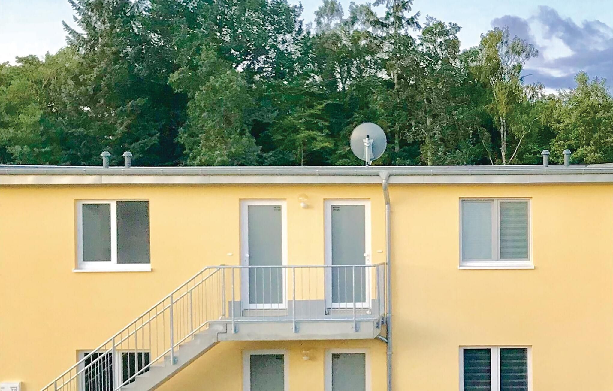 En gul bygning med balkon, vinduer og parabolantenne.