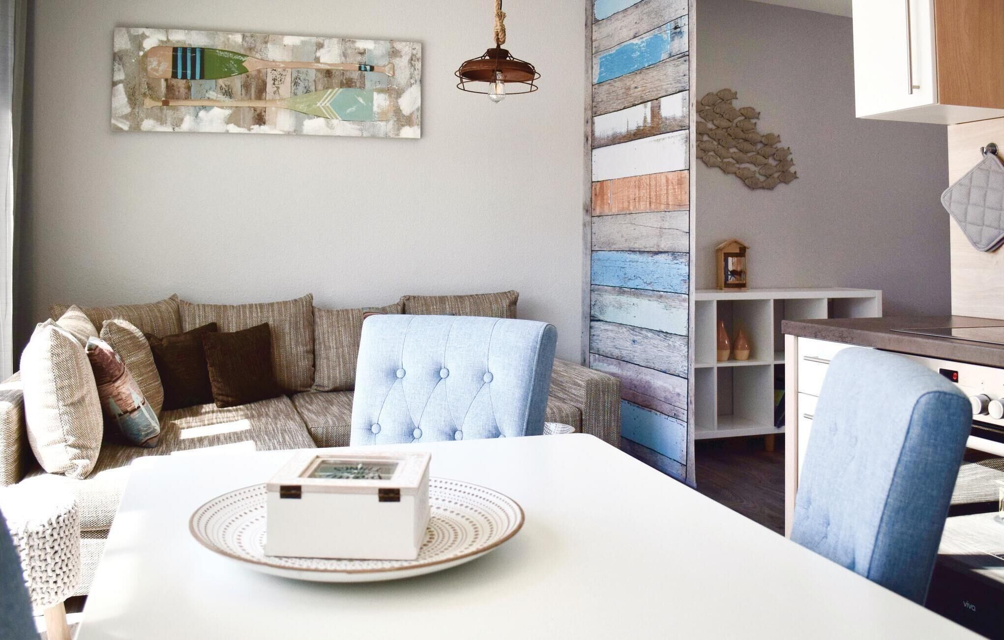Ein gemütliches Wohnzimmer mit einer Couch, einem Esstisch und einer dekorativen Schachtel, sowie einer Wand mit Holzpaneelen.