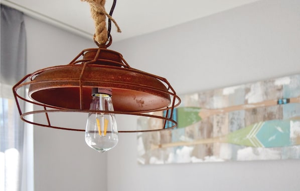 A rustic metal pendant light fixture with a visible bulb, hanging from a braided rope.