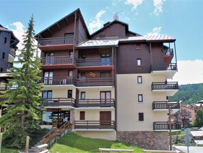 A multi-story hotel with balconies, wooden railings, and a stone base. - Studio for 4 near shops and slopes in Risoul (Risoul)