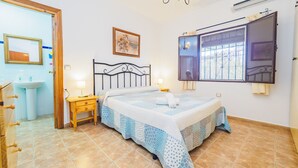 Una camera da letto con un letto, comodini, uno specchio, una finestra con sbarre e un condizionatore d'aria.