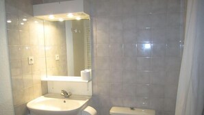 Baño con lavamanos, espejo, inodoro y cortina de ducha.