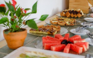 Una mesa con diferentes alimentos, incluyendo trozos de sandía y varios tipos de pasteles.