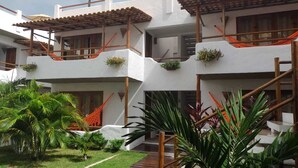 Un edificio de varios pisos con escaleras de madera al aire libre, un patio cubierto de césped y diversas plantas.