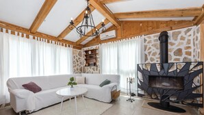 Ein gemütliches Wohnzimmer mit einem weißen Sofa, einem kleinen runden Tisch, einem Kamin und einer Steinwand.