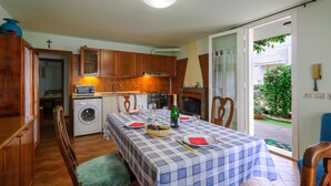 A kitchen with wooden cabinets, a washing machine, and a dining area with a checkered tablecloth. - Nice apartment in Misano Adriatico (RN) (Misano Adriatico (RN))