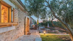 A stone building with a wooden door, outdoor seating, and a table. - Cozy home in Jagodnja Gornja (Jagodnja Gornja)