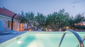 A swimming pool with a metal ladder, surrounded by stone walls and trees. - Cozy home in Jagodnja Gornja (Jagodnja Gornja)