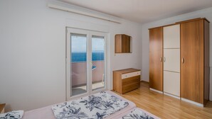 Une chambre dotée d’une grande armoire, d’une table de chevet et offrant une vue sur la mer grâce à une porte coulissante.