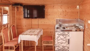 A compact kitchen with a stove, sink, and a flat-screen TV mounted on the wall. - Ferienhaus mit Fernblick (Deutschlandsberg)