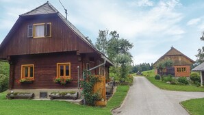 A rustic wooden house with a sloped roof, a porch with a wooden bench, and flower boxes on the windows. - Ferienhaus mit Fernblick (Deutschlandsberg)