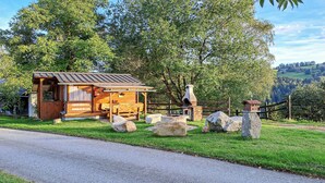 A rustic wooden cabin with a chimney, a small porch, and a stone wall. - Ferienhaus mit Fernblick (Deutschlandsberg)