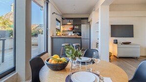 A modern dining area with a large window, a bowl of fruit, and a dining table set for four. - Romantic Terrace Hideaway in the Heart of Rome (Roma)