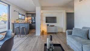 A modern living room with a grey sofa, a coffee table, and a TV mounted on the wall. - Romantic Terrace Hideaway in the Heart of Rome (Roma)