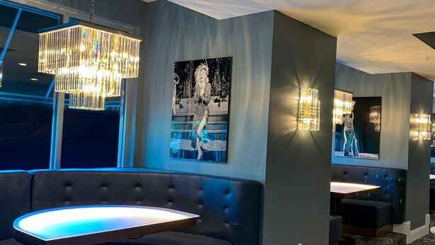 A modern hotel lobby with a seating area featuring a round table and cushioned benches. - Hotel Legends (Biloxi)
