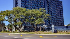 A modern building with a grid of windows, a clear sky, and a road with yellow lines. - Hotel Legends (Biloxi)