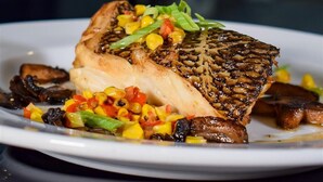 A plate with grilled fish, vegetables, and mushrooms. - Hotel Legends (Biloxi)