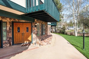 A two-story house with a stone facade, a wooden front door, and a covered porch.