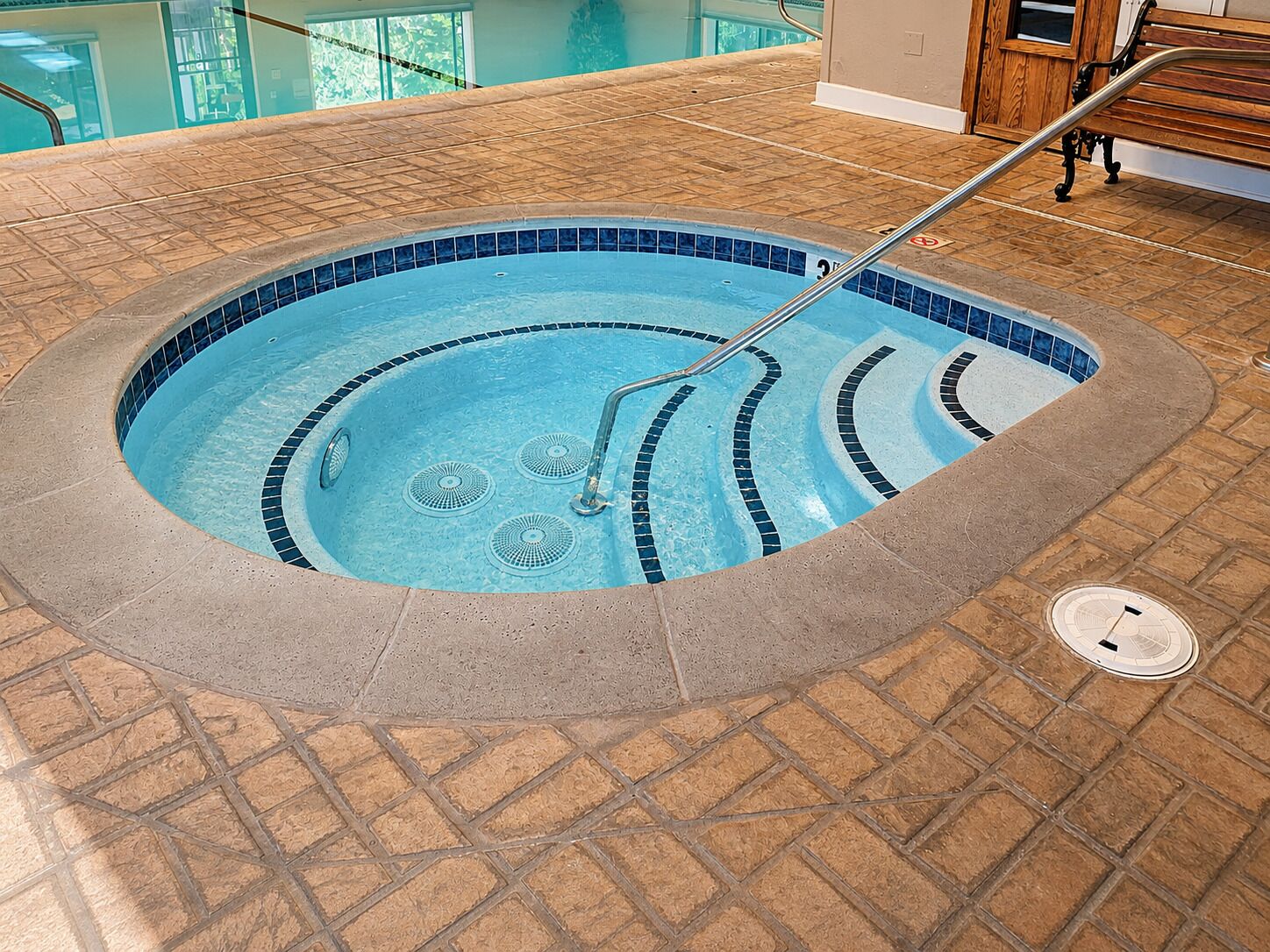 A hot tub with a tiled edge and a metal ladder.
